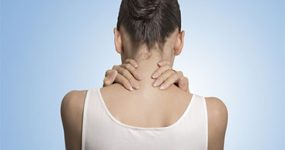 a woman in a white shirt holding her neck with both hands