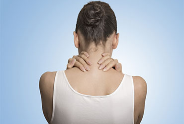 a woman in a white shirt holding her neck with both hands