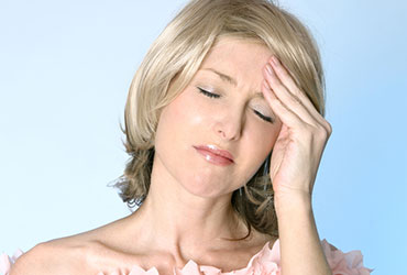 a woman holding hear forehead because of a tension headache