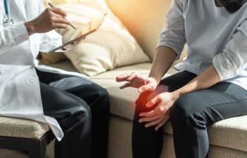 A doctor consulting a patient suffering from knee joint pain.