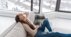 woman with headache sad sitting on couch
