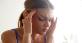 young woman with a headache massages her temples