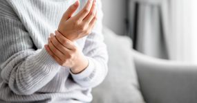 Close up view of a Young woman massaging her hand for relieve feeling wrist pain, joints aches, arthritis inflammation, peripheral neuropathies, muscle strain.