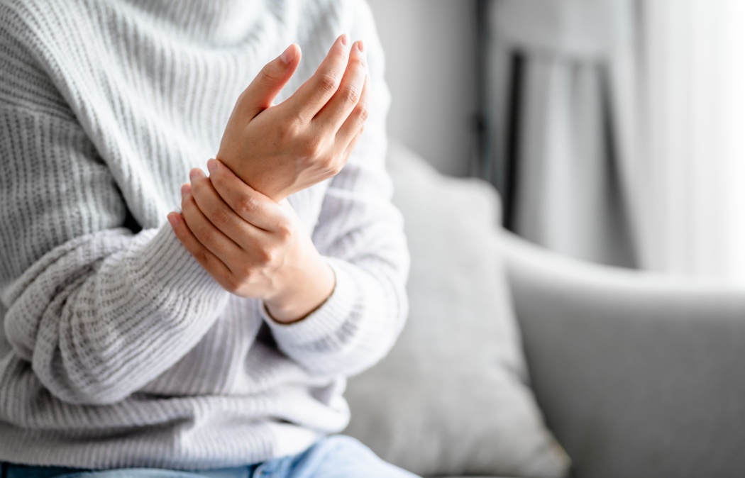 Close up view of a Young woman massaging her hand for relieve feeling wrist pain, joints aches, arthritis inflammation, peripheral neuropathies, muscle strain.