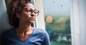 Portrait of pensive black woman standing beside window